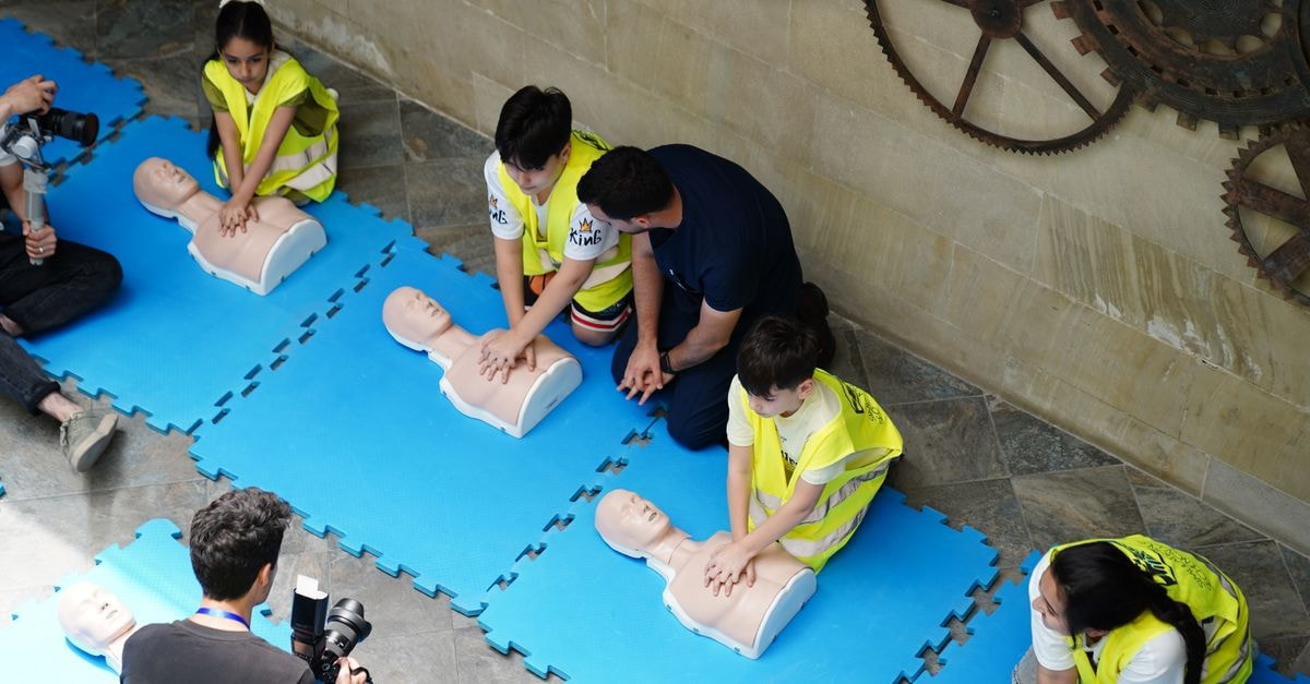 A CPR workshop in Baku, Azerbaijan featuring participants practicing on mannequins with guidance from an instructor.