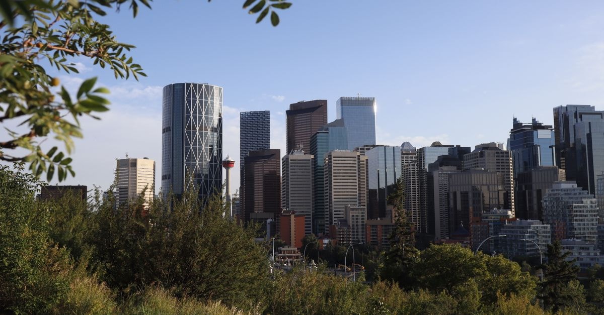 A vibrant view of Calgary's skyline with modern skyscrapers framed by greenery under a clear sky.