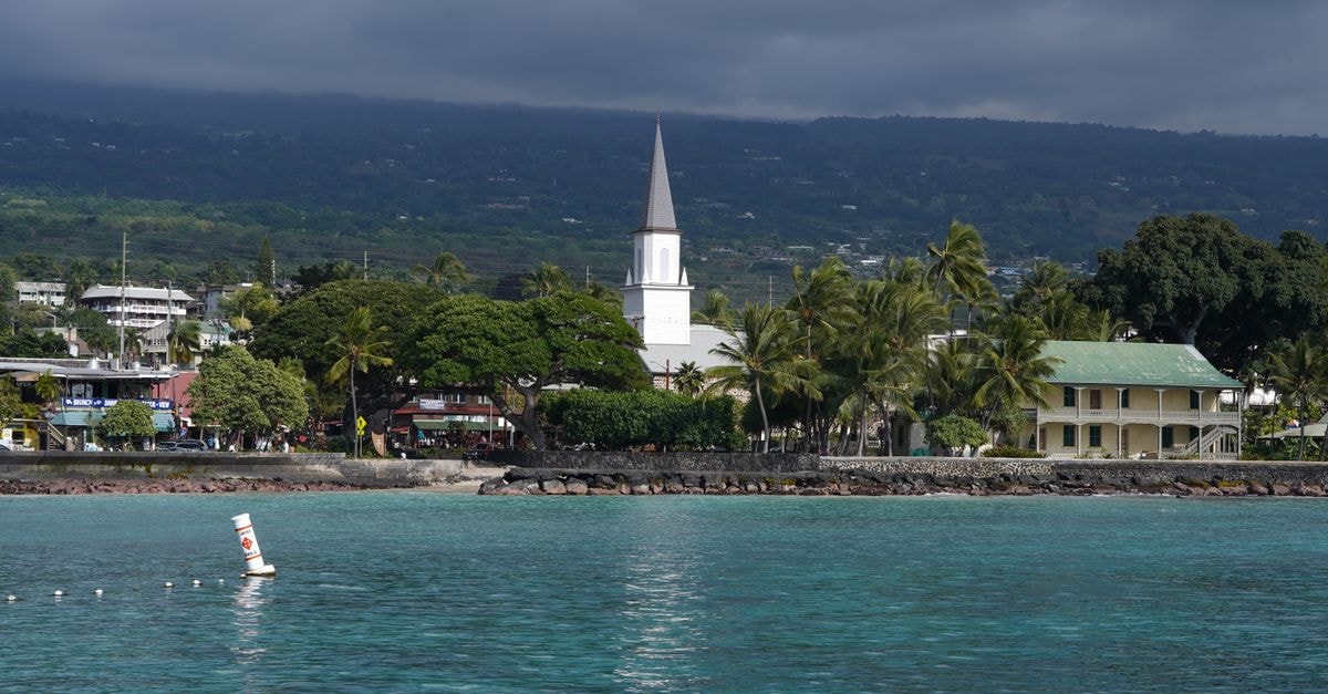 Noumea Travel Guide: Pacific Calm in a Capital Yet to Be Discovered Scenic view of Kailua-Kona waterfront featuring a historic church under cloudy skies.