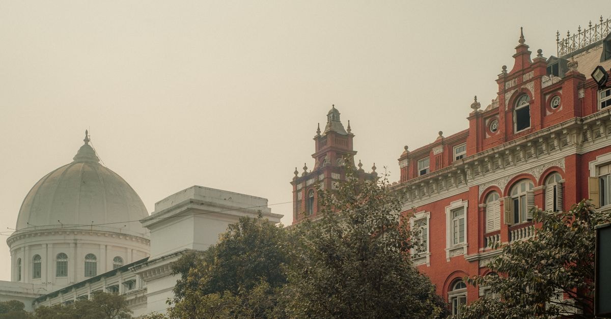 Colonial-era buildings in Kolkata showcasing iconic architectural styles under a warm hazy sky.