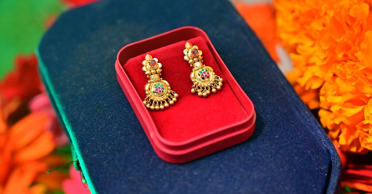 Central banks set gold-buying record in Q2 2026 as jewellery demand slumps Close-up of intricate gold earrings in a red velvet box set against vibrant flowers.