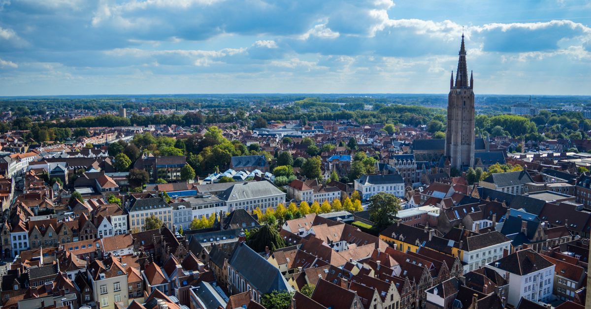 Aerial shot of Bruges cityscape showcasing the historic Belfry under a partly cloudy sky.