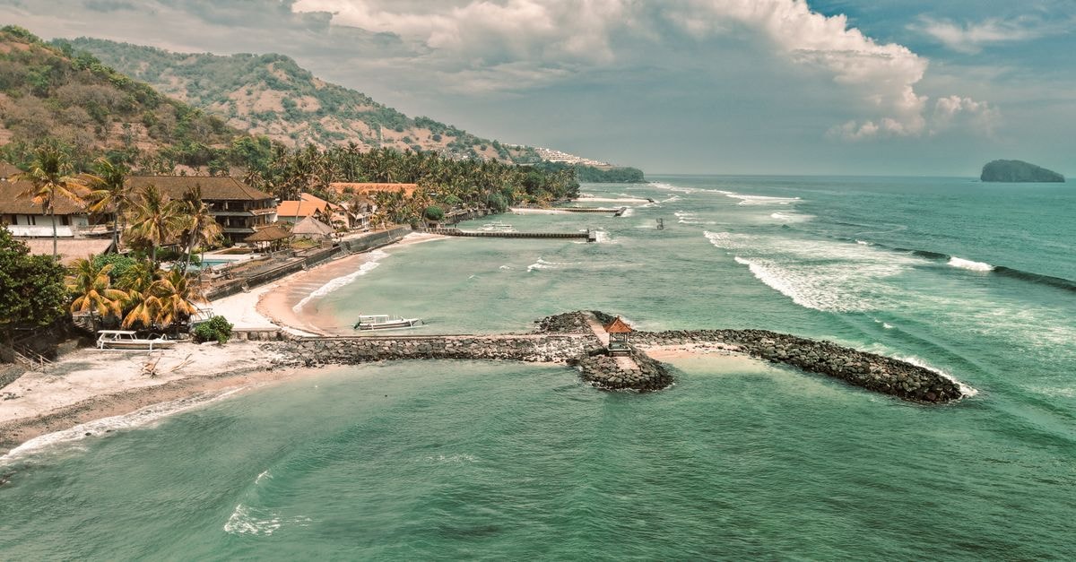 A breathtaking aerial view of a coastal landscape in Bali, showcasing clear waters and lush hills.
