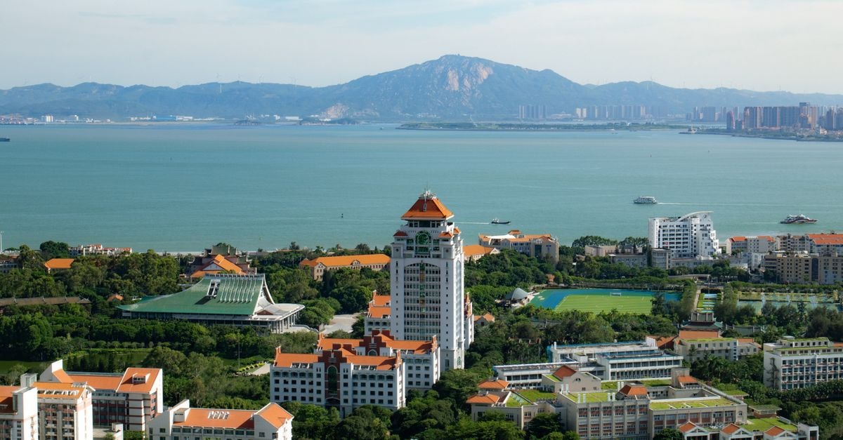 Xiamen Travel Guide: Coastal Calm, Easy Transit, and Local Flavor Aerial view of a coastal cityscape with mountains and ocean in the background.