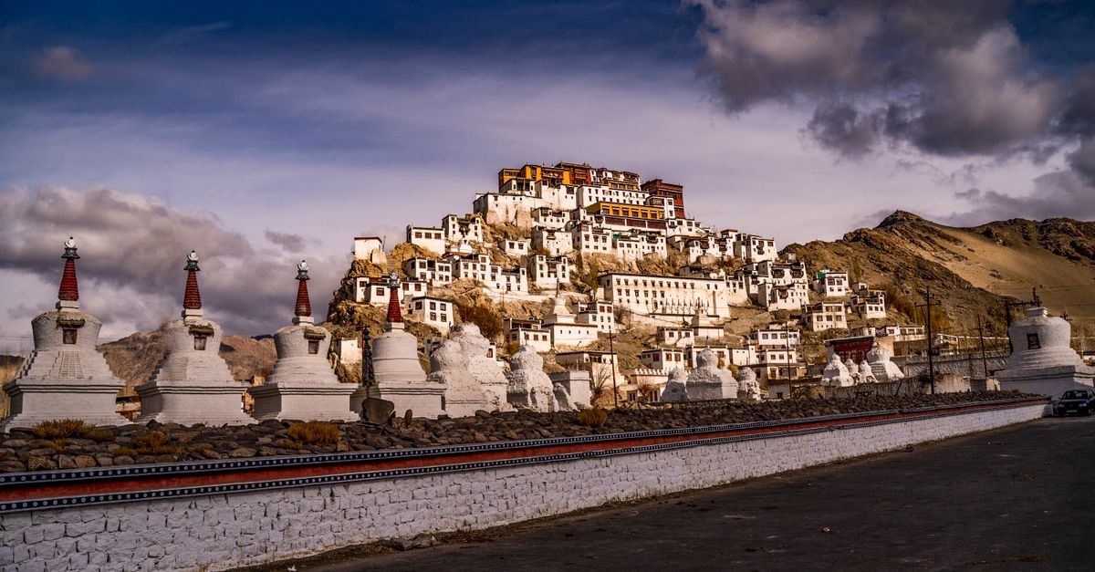 Scenic landscape of a Tibetan monastery with striking architecture against a dramatic sky.