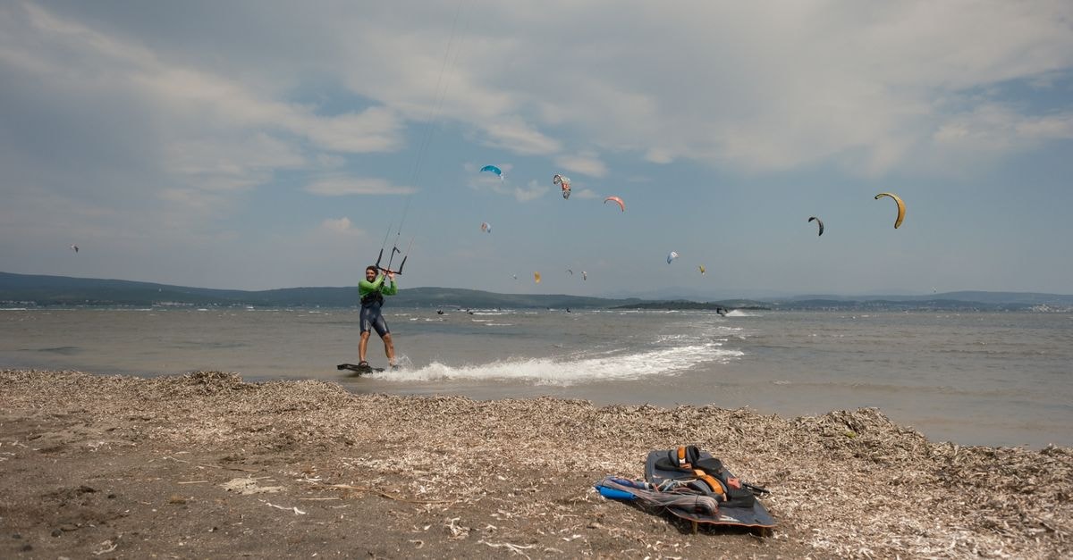 Changle Travel Guide: Kites, Lakes, and Chinese Dining A kitesurfer rides the waves on a breezy beach day, with multiple kites in the sky.