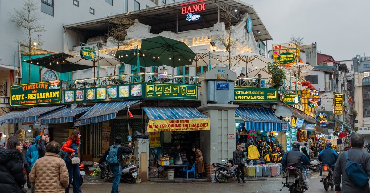 Explore the lively streets of Hanoi, Vietnam, bustling with vendors, cafes, and vibrant signs.