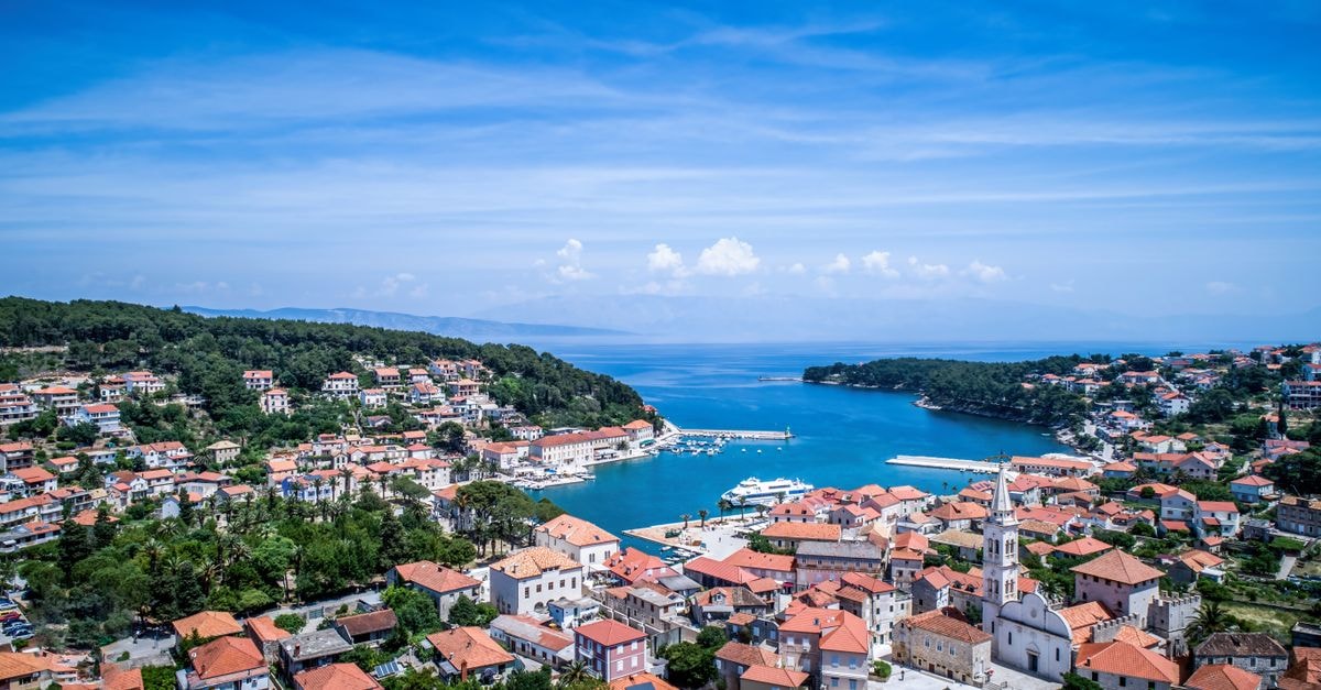 Scenic aerial view of Hvar, Croatia, with vibrant rooftops and blue Adriatic Sea under a clear sky.