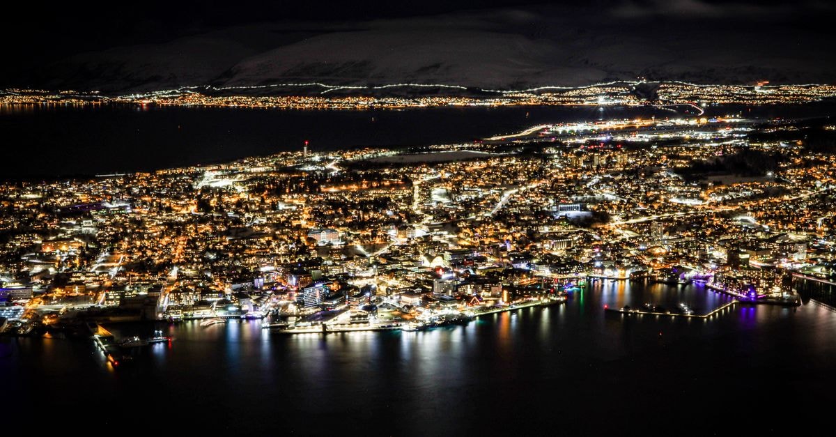 Stunning aerial view of Tromsø, Norway by night with illuminated cityscape.