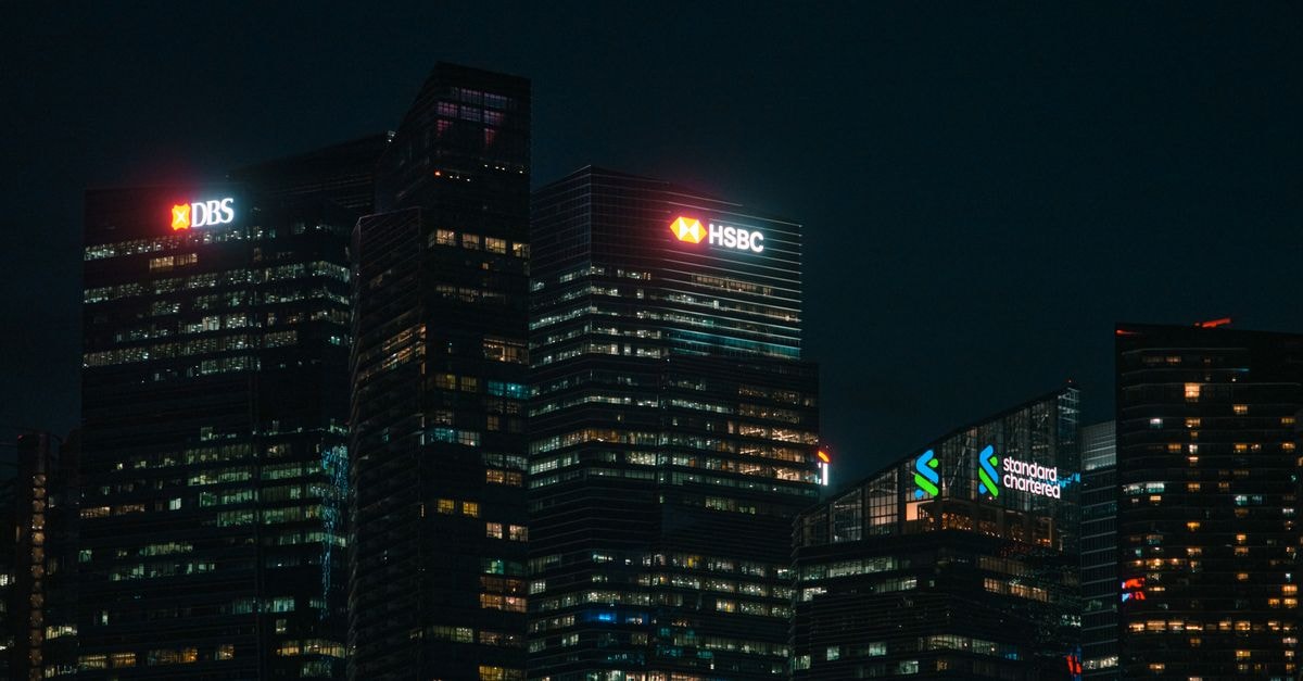 First Bancorp: Premium Bank Priced for Perfection Illuminated city skyscrapers of major banks in Singapore's financial district at night.