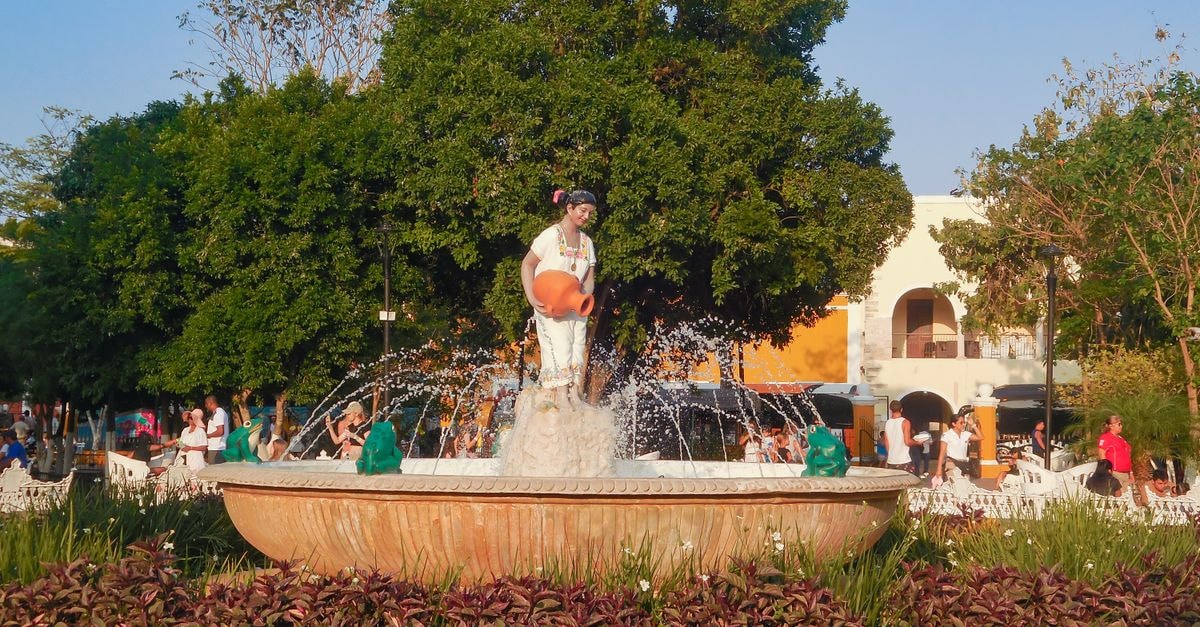Ahuachapan Travel Guide: Planning Tips, Costs and Things to Do Fountain with sculpture in a busy park surrounded by greenery and visitors during daytime.