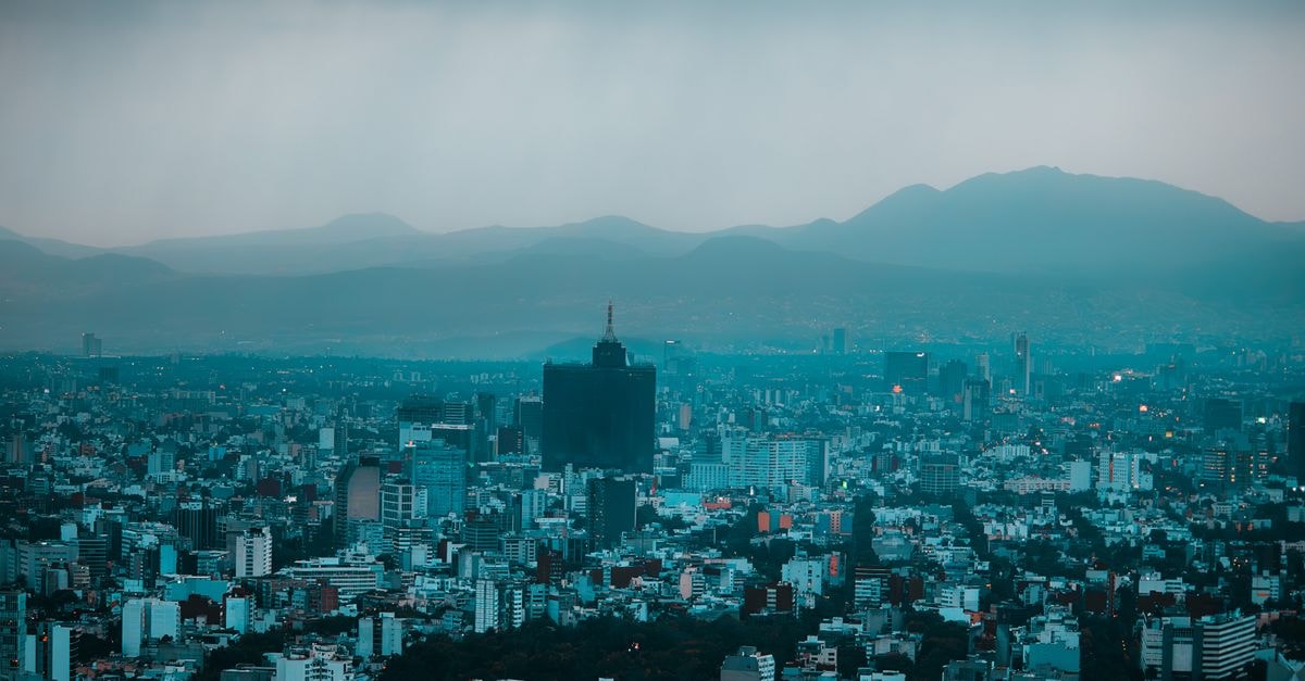 A dramatic aerial view of Mexico City skyline with mountains in the background.