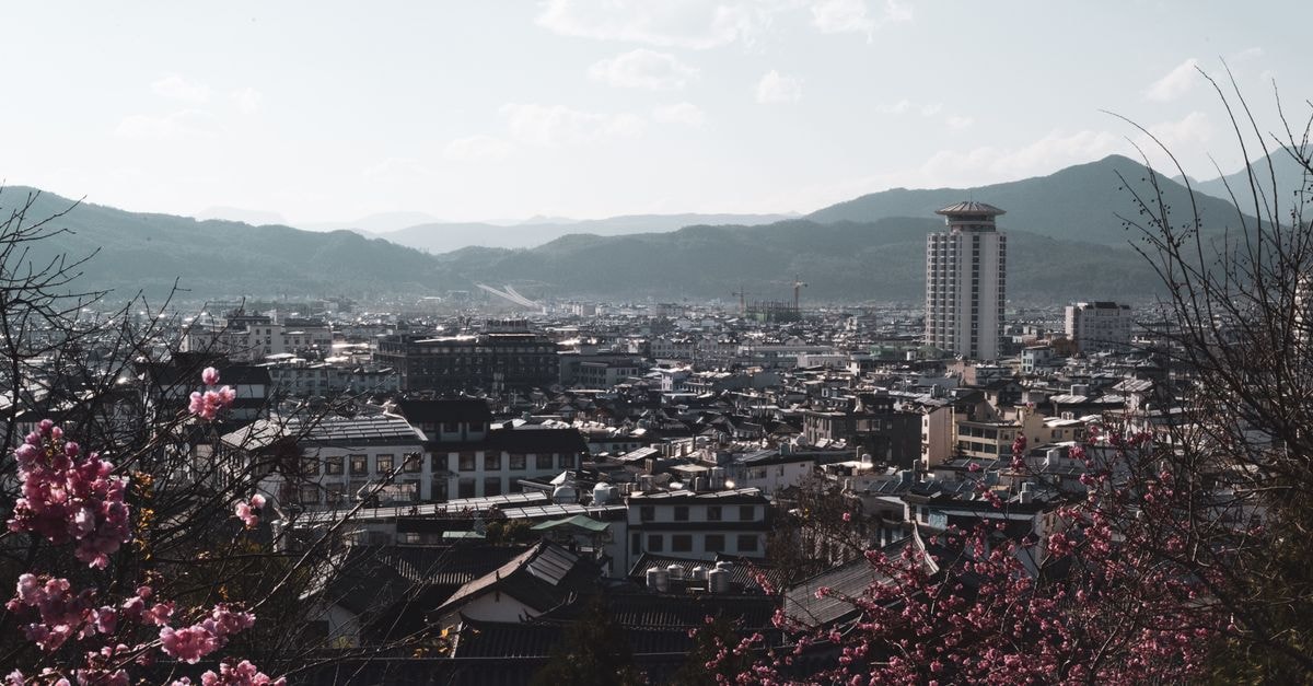 KKR Yamaguchi Asakura, Yamaguchi — Quiet Address in the Yuda Onsen District Serene aerial view of a bustling city framed by vibrant cherry blossoms and distant mountains.