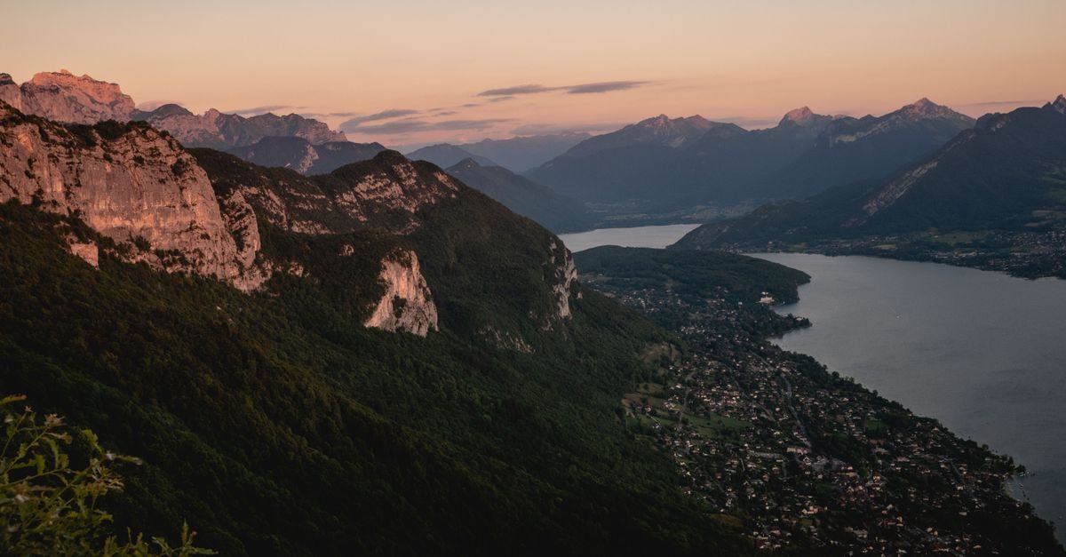 Hôtel Carlton, Annecy — A 1930s Boutique Retreat Near the Old Town Stunning aerial view of Annecy's mountains and serene lake at sunset in France.