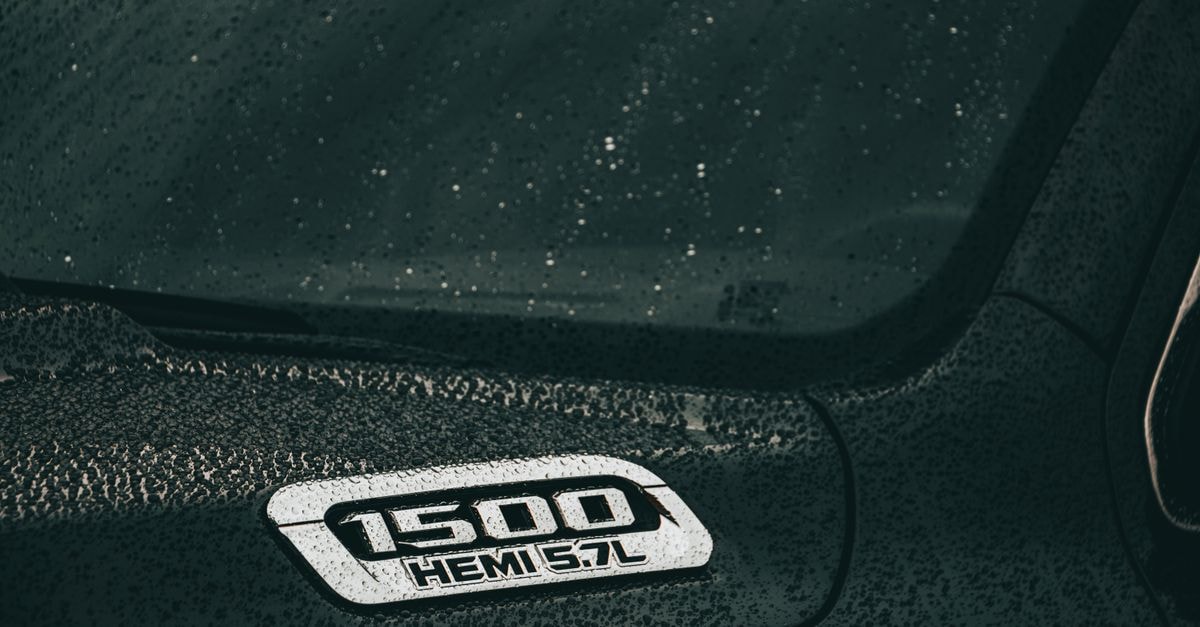 A close-up of a black Dodge Ram 1500 Hemi with rain droplets on the surface, showcasing automotive design.