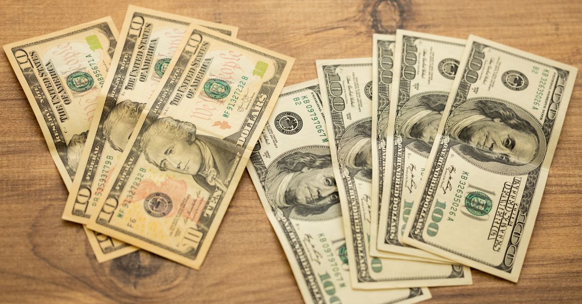 A collection of US dollar bills arranged on a wooden surface, showcasing currency denominations.