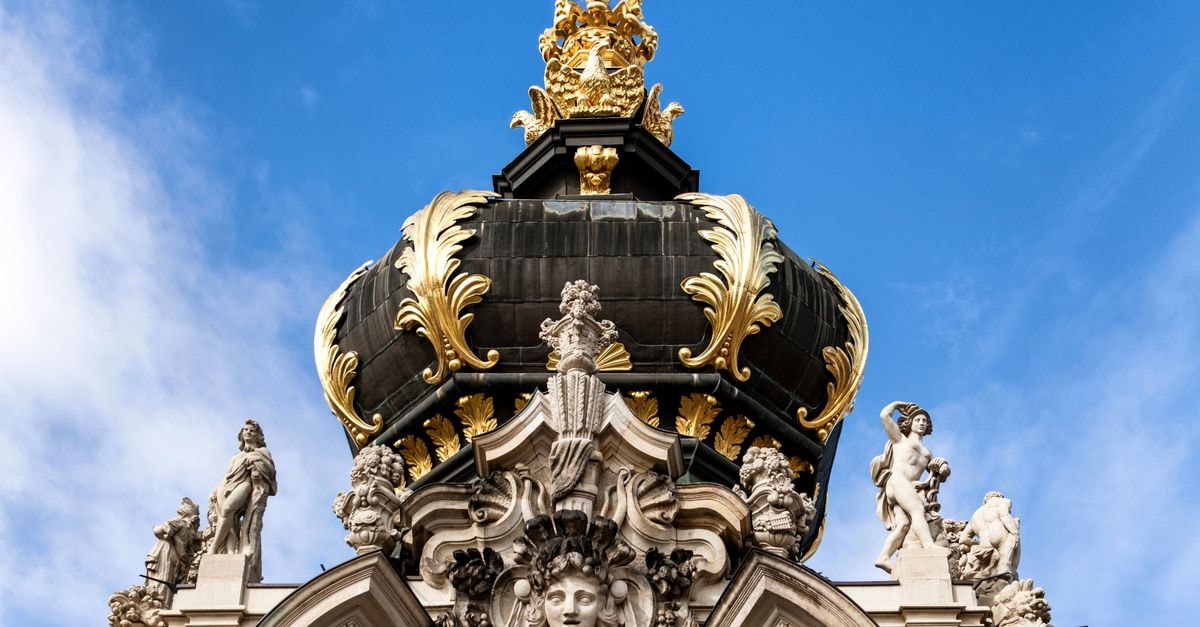 Close-up of the elaborate Kronentor pavilion in Dresden, showcasing its sculptures and ornate crown against a blue sky.