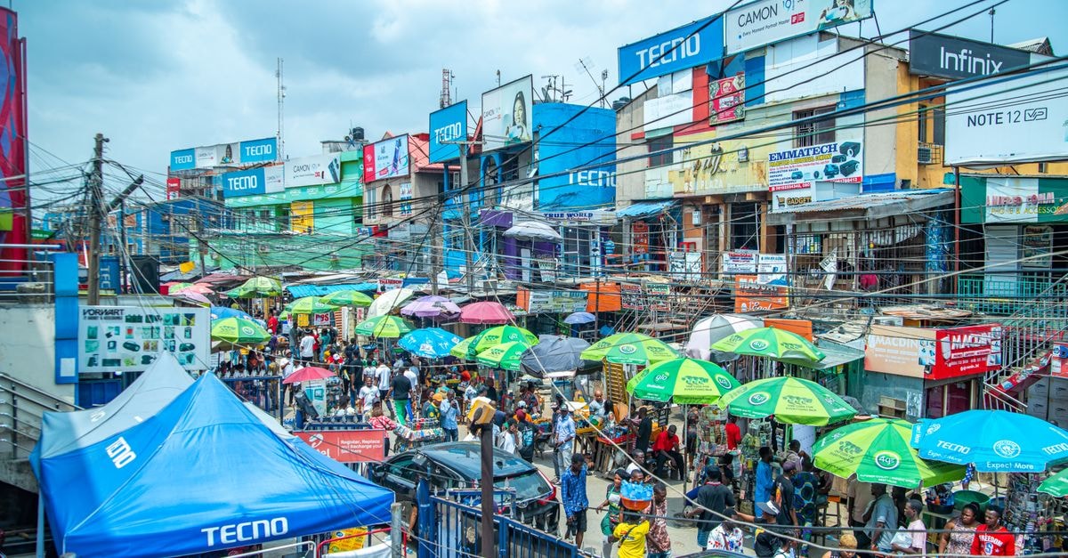 Ota Travel Guide: Markets, Campus Strolls and Yoruba Heritage A bustling market with colorful umbrellas and billboards in Lagos, Nigeria.