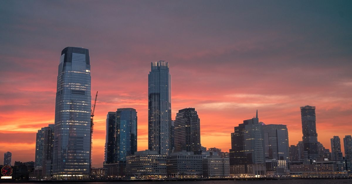 The Westin Jersey City Newport: Manhattan-Skyline Views on Washington Boulevard Stunning view of New York City skyline with a vibrant sunset reflecting on skyscrapers.