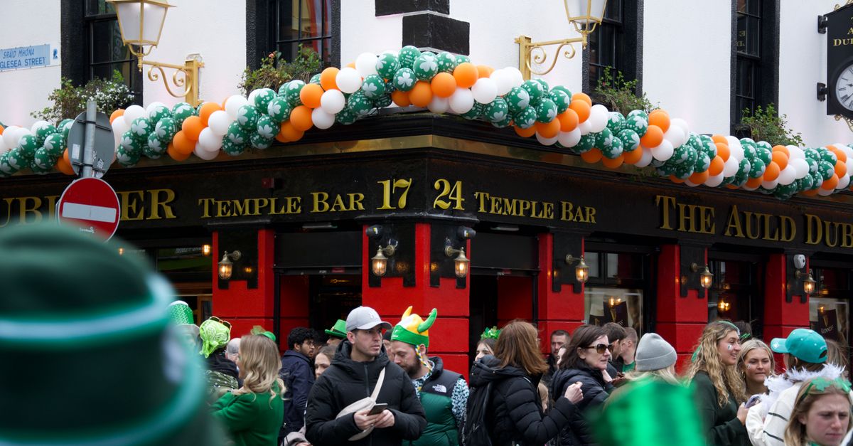 Festive crowd outside Temple Bar in Dublin during St. Patrick's Day with green decorations.