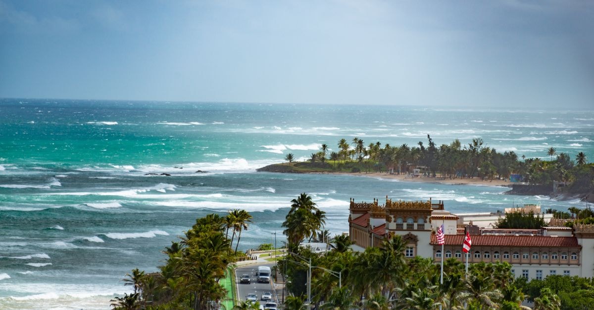 A breathtaking aerial view of a tropical coastline with waves crashing against the shore and lush palm trees.