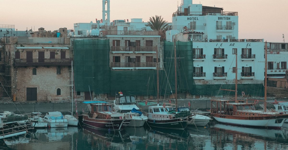 The Colony in Kyrenia: A Boutique Retreat by the Harbor and Byzantine Castle Scenic view of Kyrenia harbor at sunset with moored boats and historic buildings.