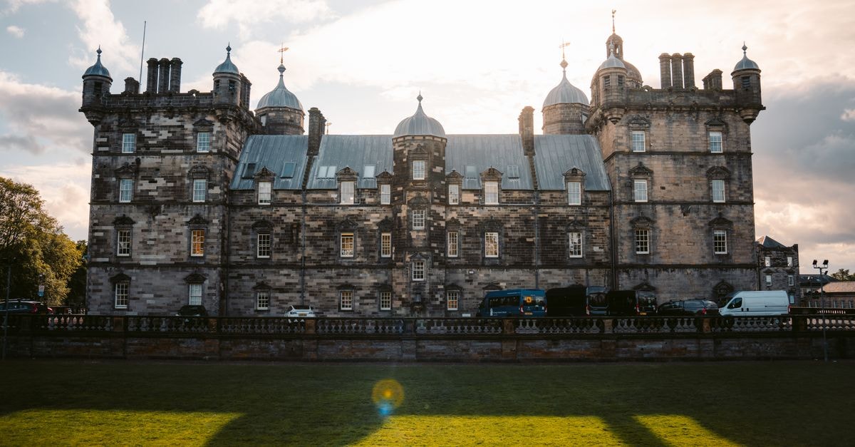 A Thoughtful Aberdeen Travel Guide for Curious Visitors A dramatic view of a historic castle with a sunlit sky and lush greenery in the foreground.