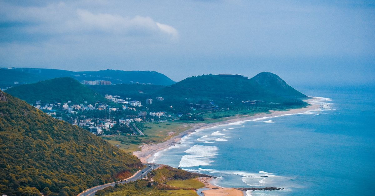 Visakhapatnam Travel Guide: Planning Tips, Costs and Things to Do A breathtaking aerial view of the coastline in Visakhapatnam, capturing lush hills and the vibrant sea.