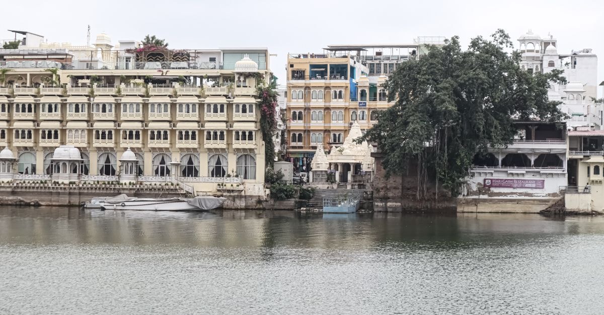 Raghu Mahal Hotel & Flames Restaurant, Udaipur — A Downtown Stay with On-Site Dining Picturesque view of Udaipur's historic lakeside architecture reflecting on calm waters.