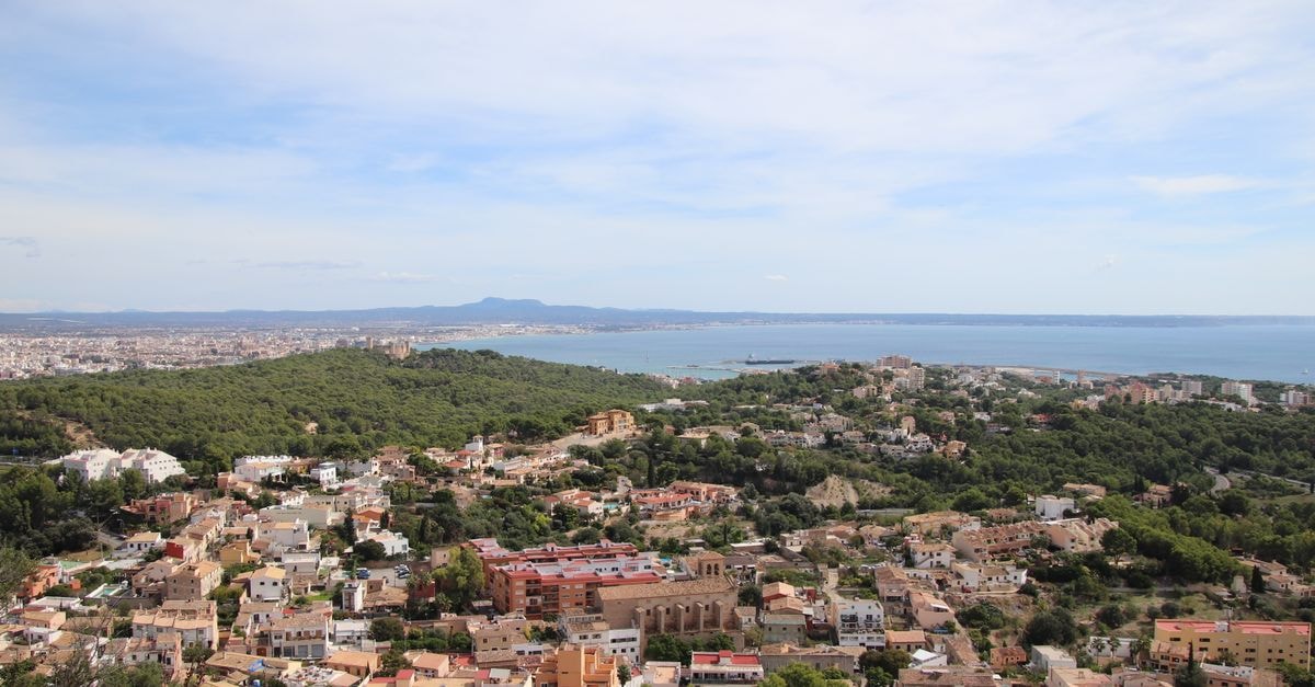 Samaritana Suites in Palma: Boutique Apartments in the Old Town Breathtaking aerial view of a coastal cityscape with lush greenery and serene ocean backdrop.