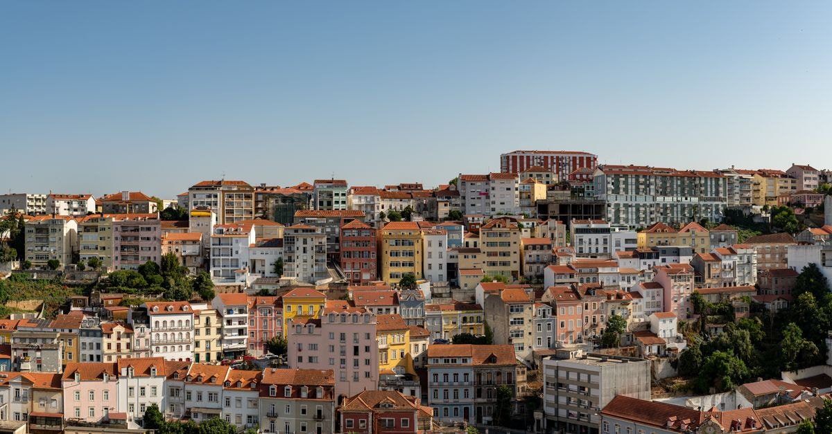 Coimbra travel guide: a slow weekend in Portugal's student city Panoramic view of Coimbra's vibrant, colorful buildings under a clear blue sky.