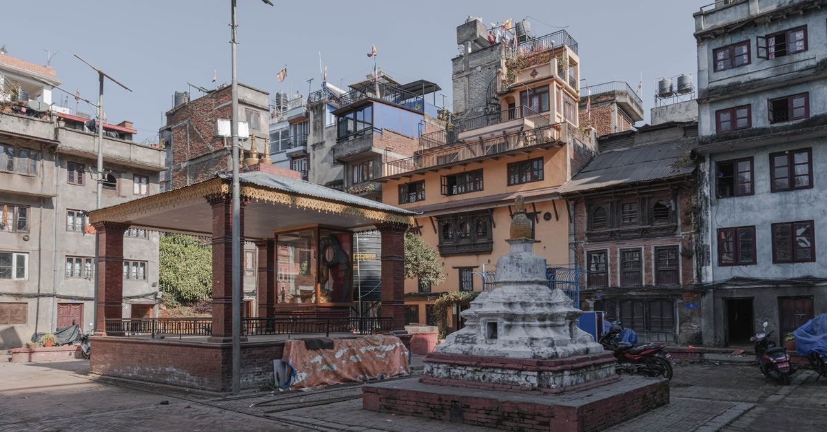 Kathmandu travel guide: timeless rituals meet city streets Quaint square in Kathmandu featuring a stupa and traditional Nepali architecture.
