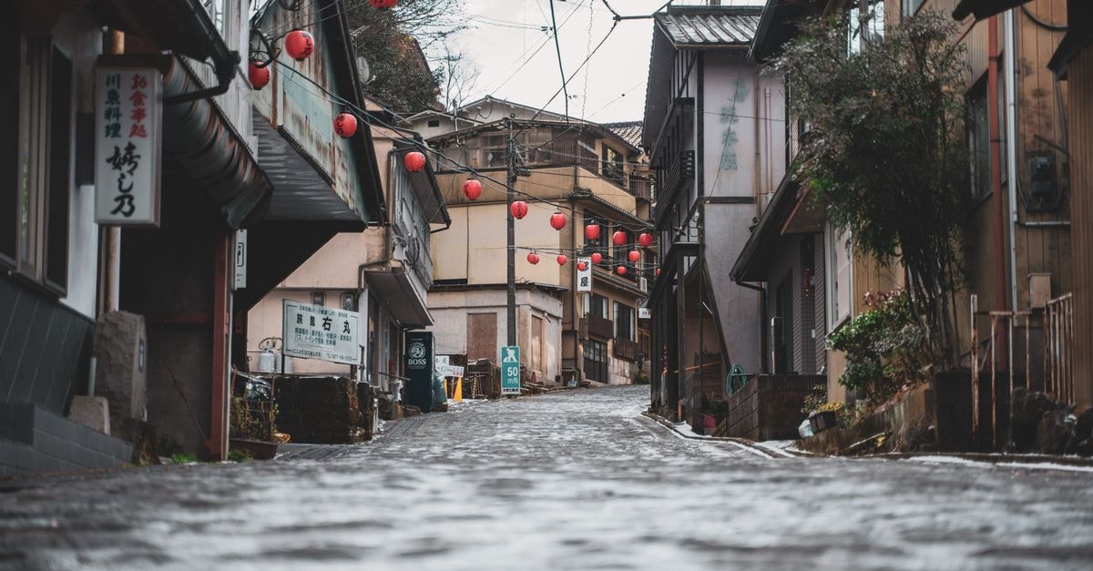 Hirakata Travel Guide: A Quiet Osaka Border Town Worth a Stop A picturesque rainy day view of a cobblestone street with red lanterns in Osaka, Japan.
