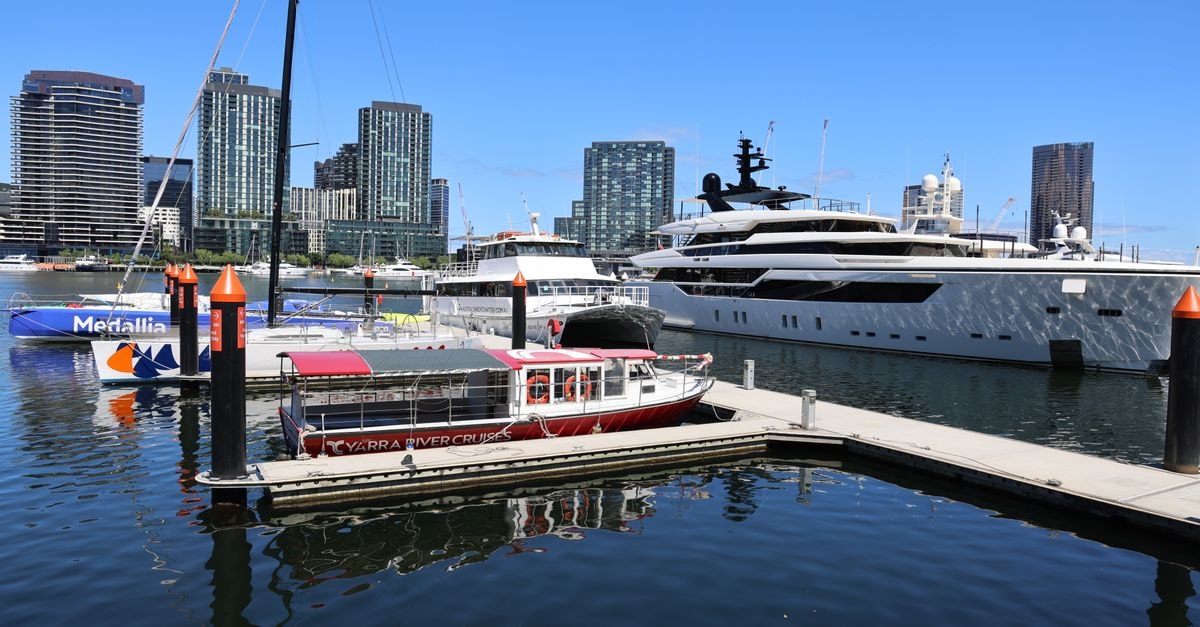 Melbourne Travel Guide: Where Laneways, Sport and Plates Meet A sunny view of luxury yachts docked at Melbourne's Docklands Marina, reflecting vibrant cityscape.