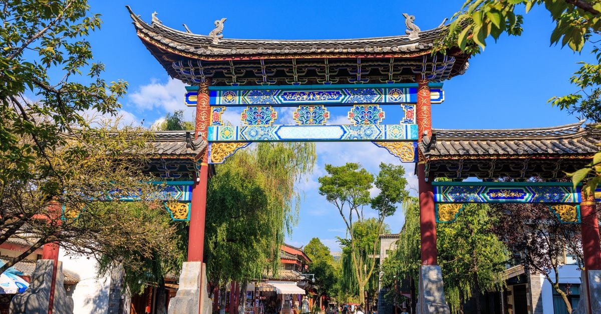 Slow Strolls and Quiet Corners: A Jianshui Travel Guide Vibrantly painted Chinese gate in a picturesque courtyard on a sunny day.