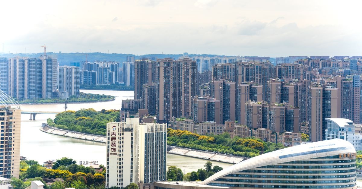 Xuzhou Hanzhong Fuxi International Hotel — A Corner Address on South Jiefang Road Aerial view of a modern cityscape with tall buildings and a winding river.