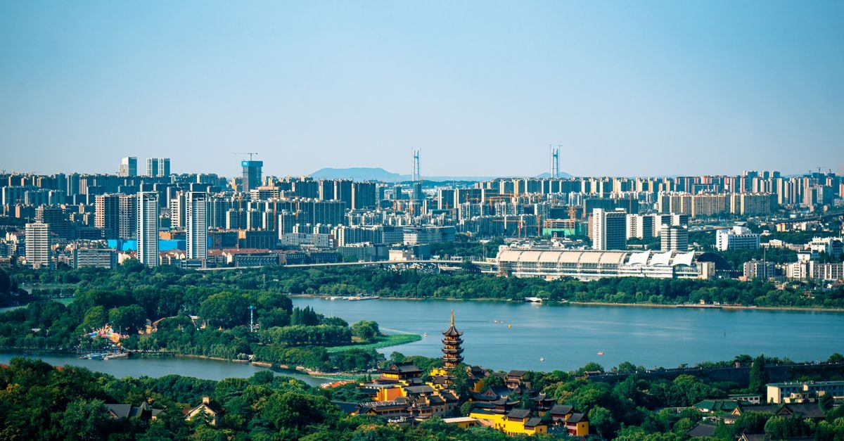 Nanjing Travel Guide: Getting Around, Sights and Food Scenic aerial view showcasing a vibrant city skyline, serene lake, and traditional temple, perfect for travel themes.