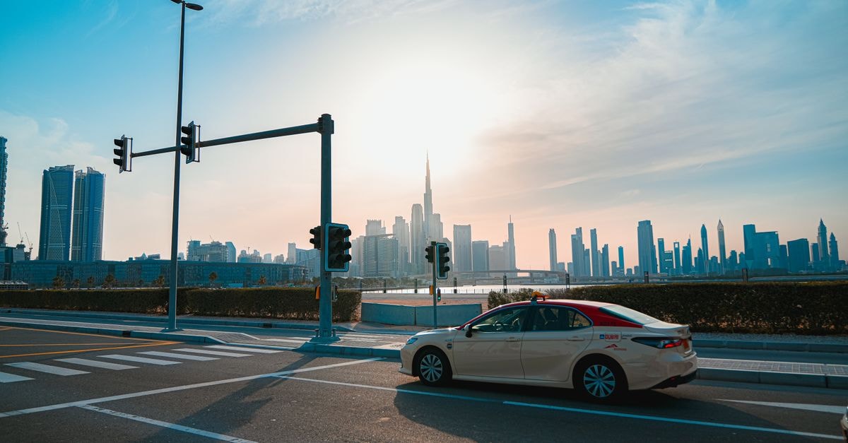 A cityscape photo featuring the iconic Burj Khalifa and a taxi in Dubai during the day.