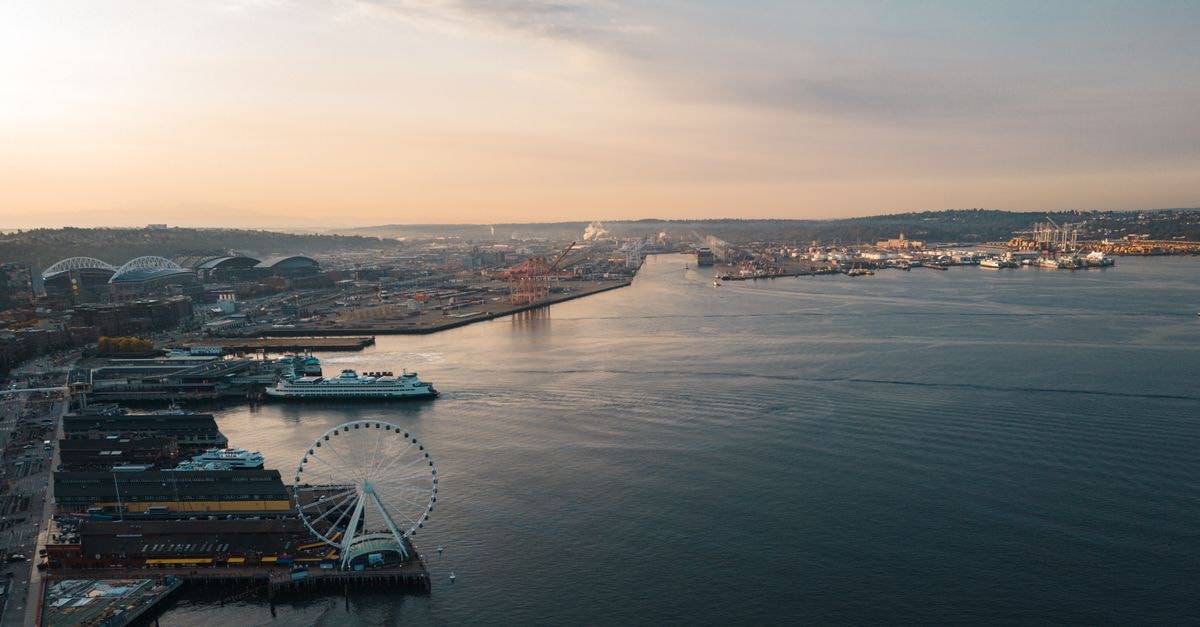 Olympia, Washington Travel Guide: A Slow Capital on Puget Sound Scenic aerial view of Seattle waterfront with ferris wheel at sunset, showcasing urban landscape.