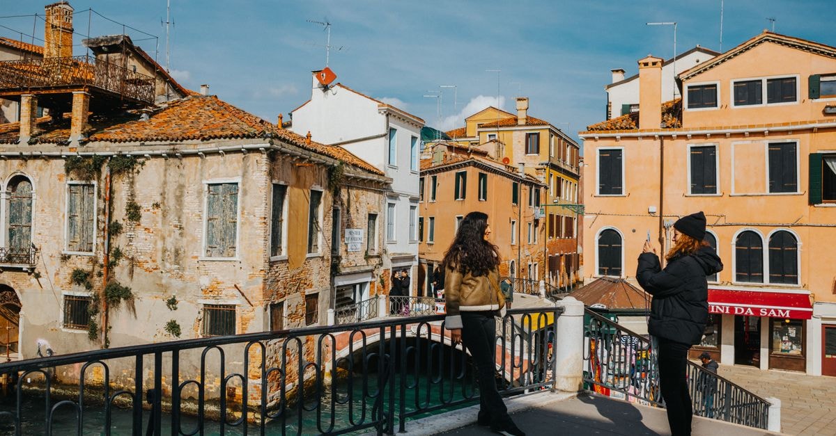 Two tourists admire the scenic architecture and waterways of Venice, Italy on a sunny day.