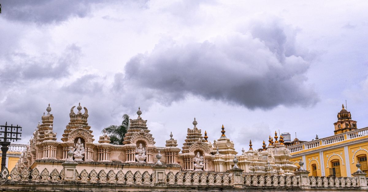 Intricate architectural details on the wall of Mysore Palace, India, under a cloudy sky.