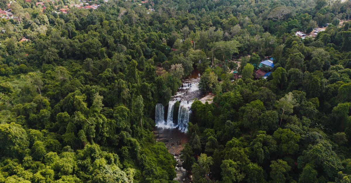 Stunning aerial view of a waterfall surrounded by dense forest in Popel, Siem Reap, Cambodia.