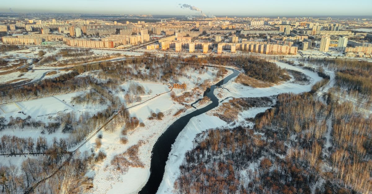 Tambovskaya Hotel in Tambov: A Quiet City-Centre Address Since 2015 Aerial view of winter landscape in Minsk, showcasing snow-covered cityscape and winding river.