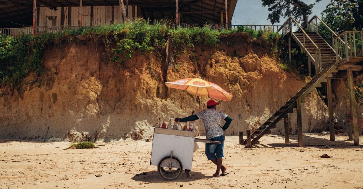 A Slow Travel Guide to Rondonópolis, Brazil's Quiet Heartland A beach vendor with an ice cream cart under an umbrella at Nazaré Beach, Brazil.