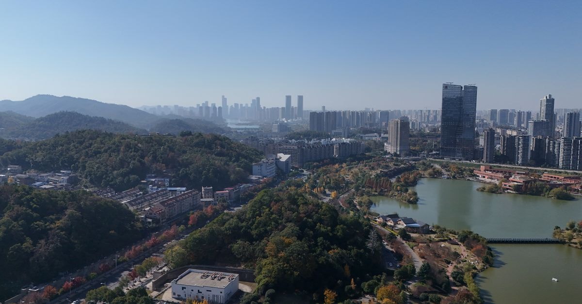 Aerial cityscape of Changsha, China, showcasing vibrant hills and a sprawling urban skyline under a clear blue sky.