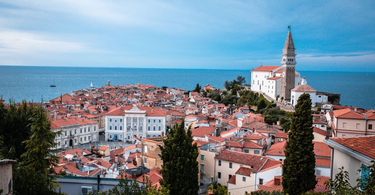 B&B Centrum Izola in Izola: Renovated Fisherman's House in the Town Center Scenic view of a coastal town featuring historic buildings and church by the sea.