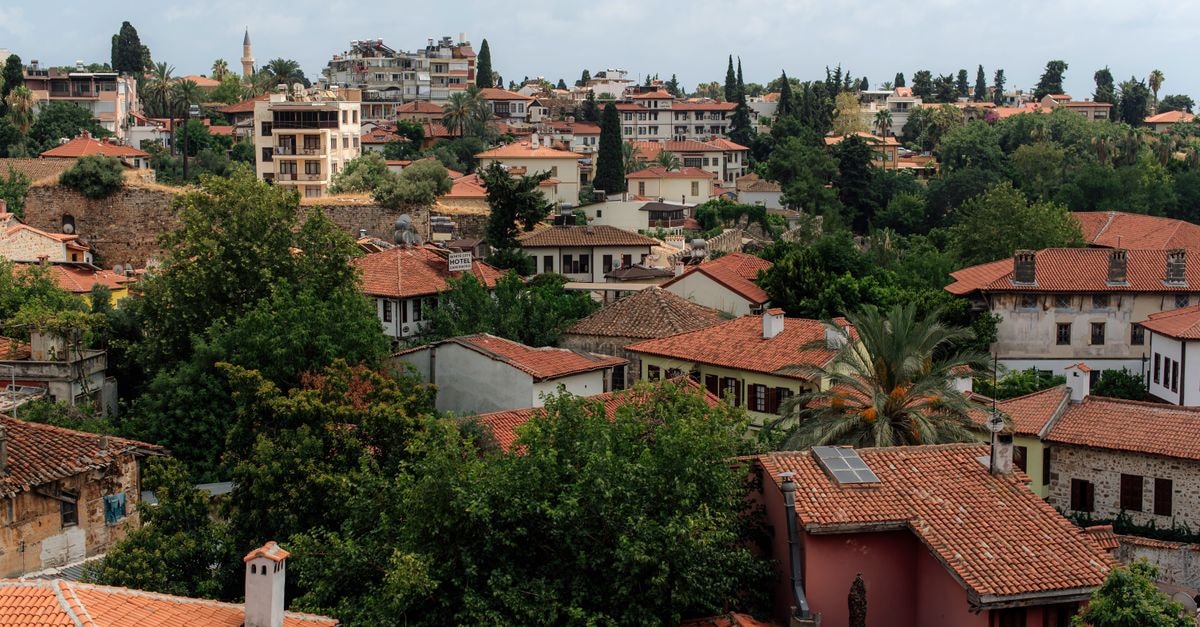 Argos Hotel in Antalya: A Heritage Stay Inside Kaleiçi A scenic view of Antalya's old town with red-tiled rooftops and lush greenery.