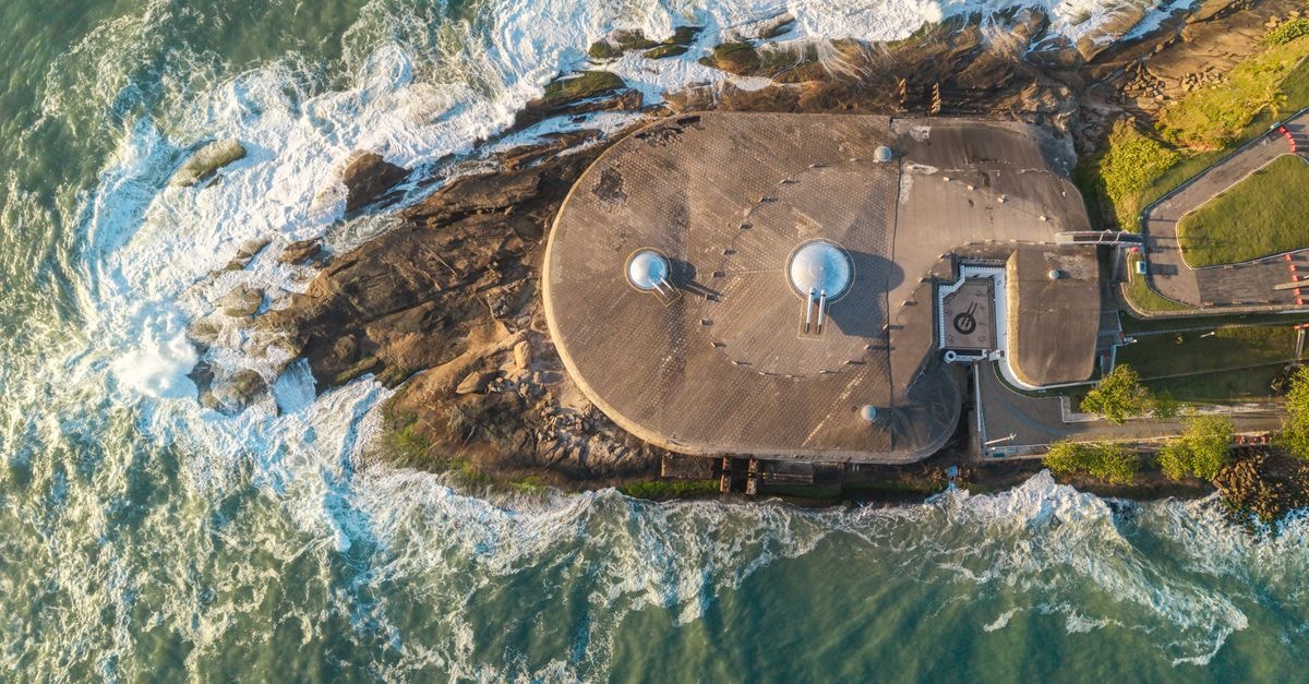 Boké Travel Guide: River Views, Fort Ramparts, and Guinea's Atlantic Edge Stunning aerial view of Fort Copacabana in Rio de Janeiro with waves crashing against the rocky shoreline at sunset.