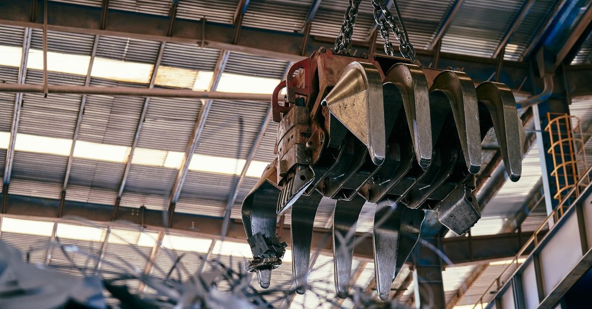 Mueller Water Products: Quality at a Cyclical Price Large industrial crane handling scrap metal in a warehouse setting.