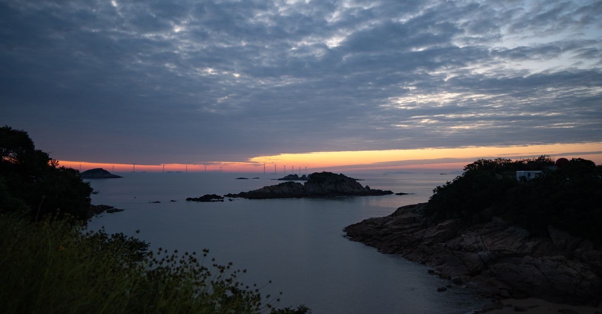 Tranquil coastal scene at sunset in Zhejiang, China, capturing serene sky and water.